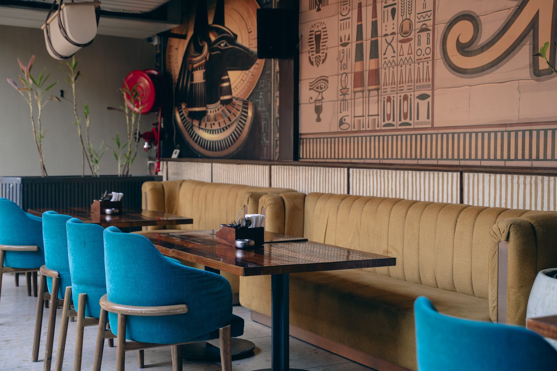 Booth seating with teal chairs under hieroglyph panels